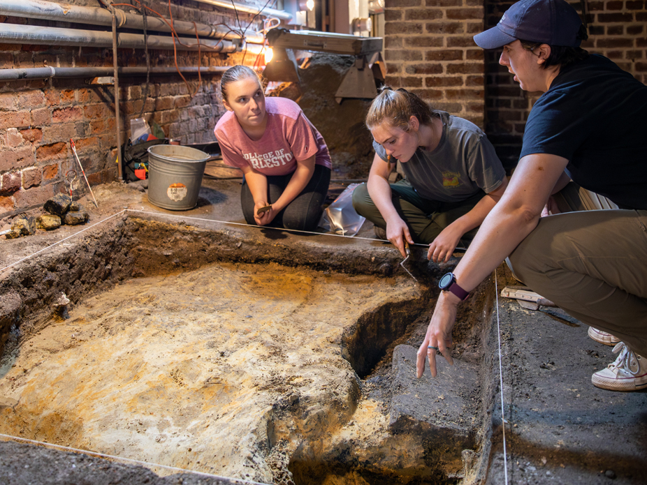 Archaeology students examining a dig site, discussing findings while working collaboratively on an excavation.