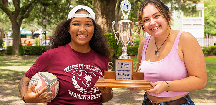 two college of charleston students holding their trophy for winning their rugby match.
