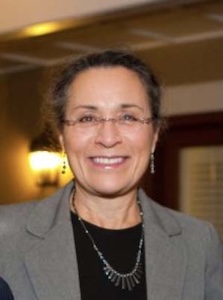 A smiling woman name Arlinda Locklear wearing glasses and a gray blazer indoors.