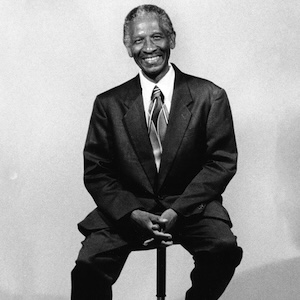 Black-and-white portrait of Eddie Ganaway, the first African American student to graduate from the College of Charleston, sitting on a stool.