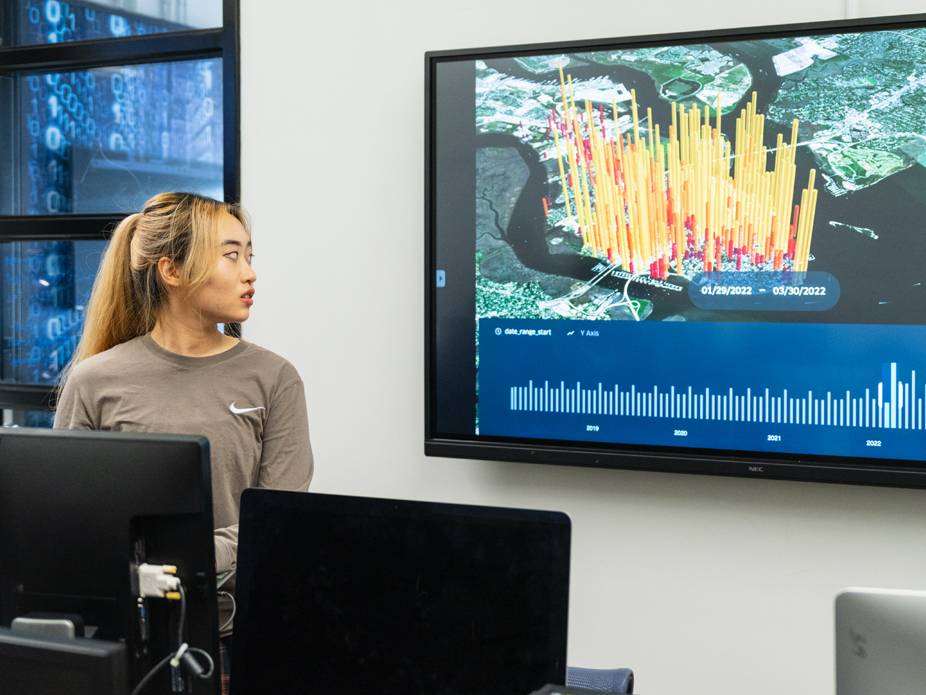 A female College of Charleston student analyzes data displayed on a large screen.