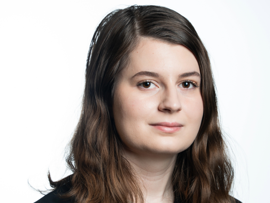 Image of a woman with brown hair smiling in front of white background