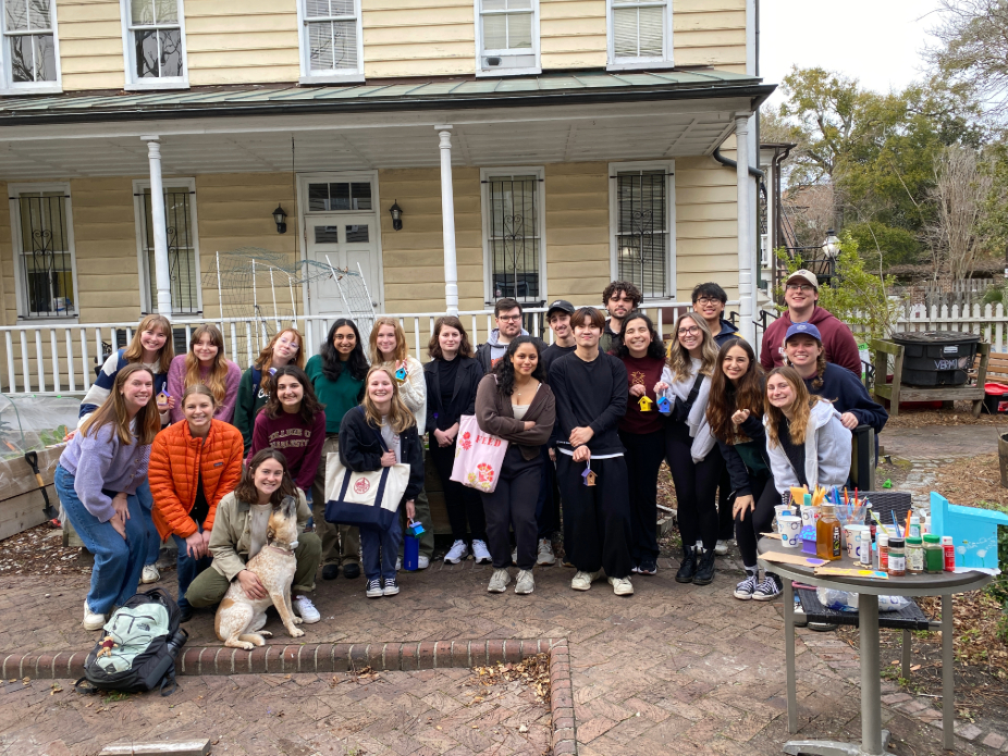 A group of people smiling in from of a house with craft supplies.