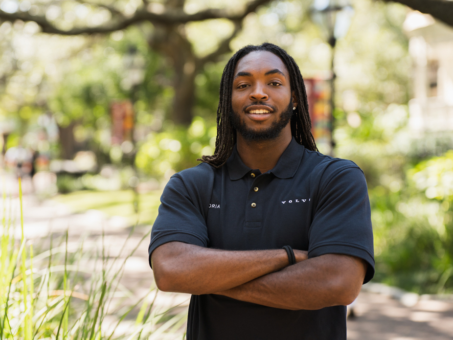 Portrait of A.J. Smith confidently folding his arms and wearing a dark "Volvo" polo shirt.