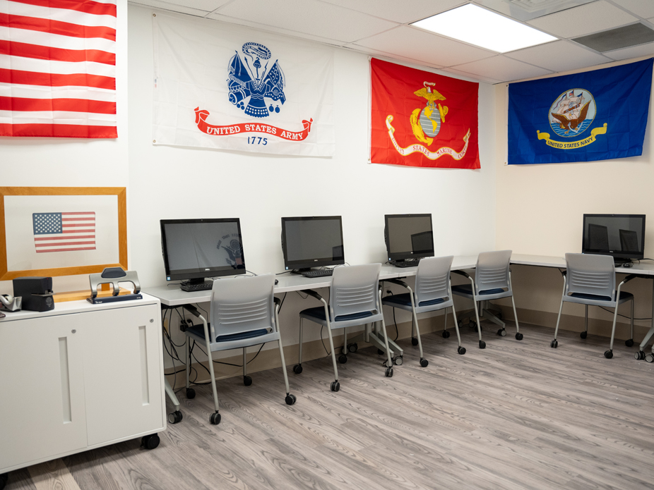 College of Charleston's Veterans and Military Lounge with numerous computer stations and military branch hanging on the walls.