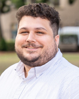 Matt Griffin, a smiling man with curly hair and a beard wearing a white collared shirt.