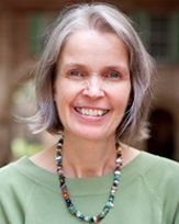 Anne Muldrow, a smiling woman with silver hair wearing a green sweater and a beaded necklace.
