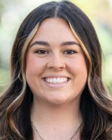 Hannah Norman with long, wavy hair and a natural background.