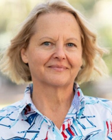Rita Wedge. a smiling woman with short blonde hair, wearing a brightly patterned shirt.