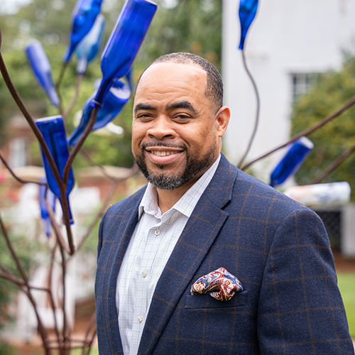 African American man standing in front of a blue bottle tree