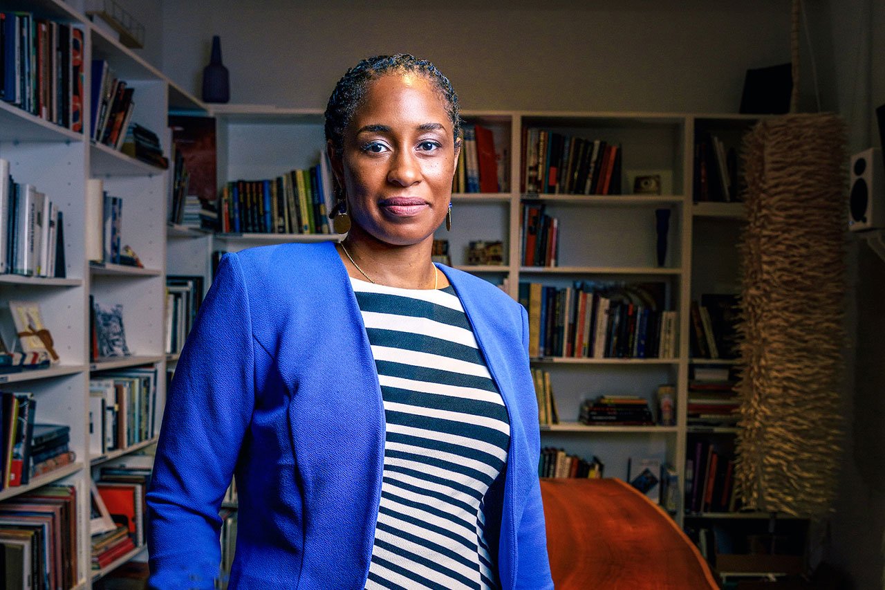 Photograph of Dr. Kameelah Martin, an African-American woman standing in front of several bookshelves. 