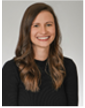 Professional headshot of a woman with long brown hair, smiling against a neutral background.