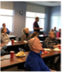 A group of engaged attendees listens attentively during a presentation in a classroom setting.
