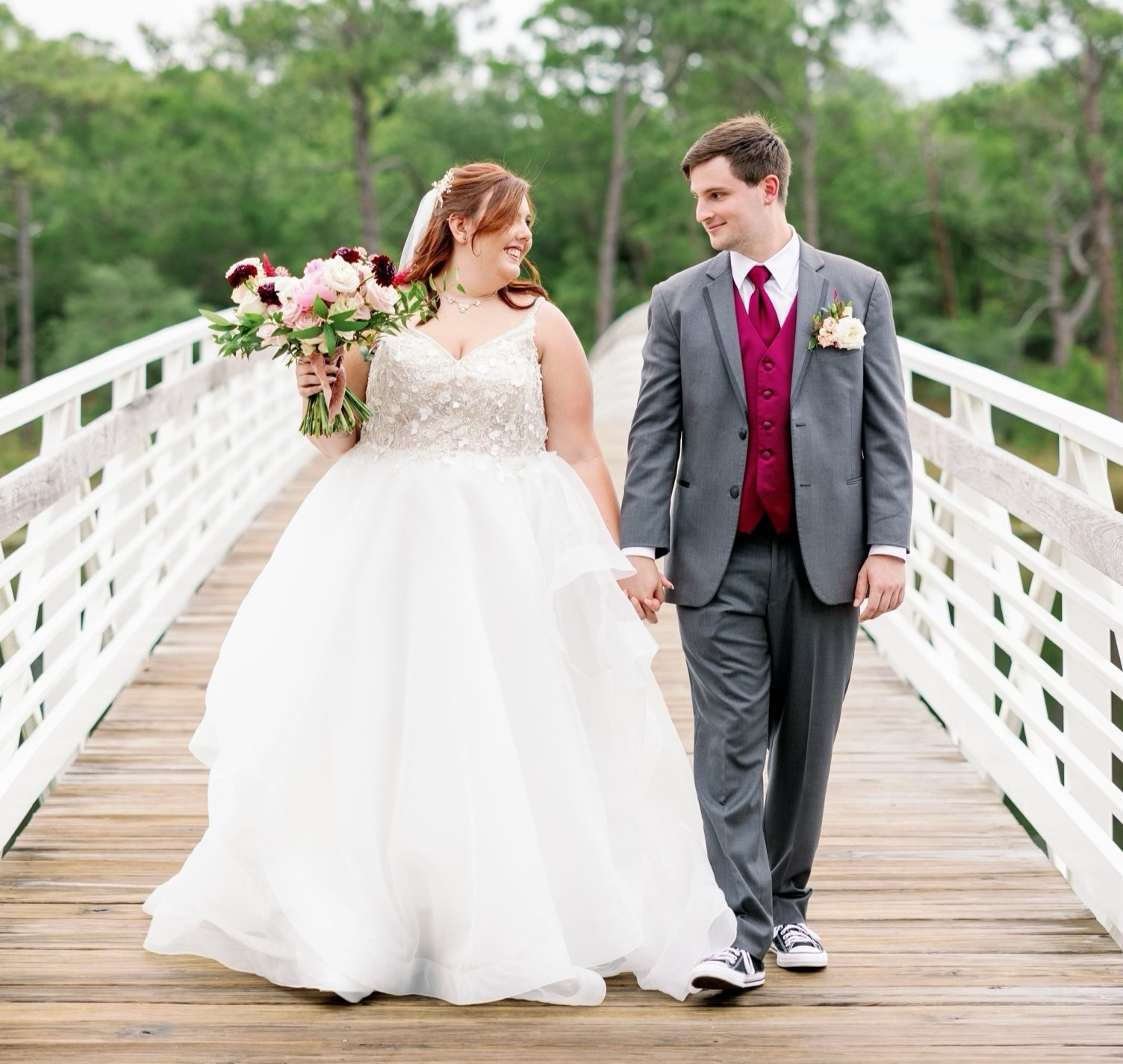 woman in wedding dress and man in suit. they are holding hands in their wedding photo.