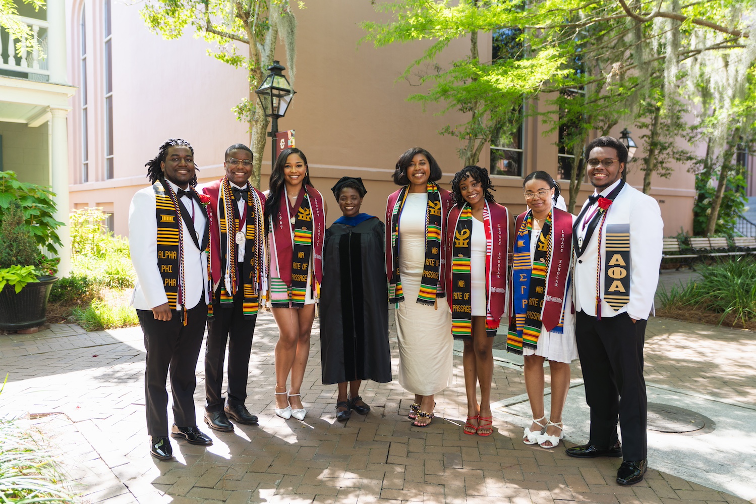 A group of graduates from the Legacy Program standing next to Director Valerie Frazier at a graduation.