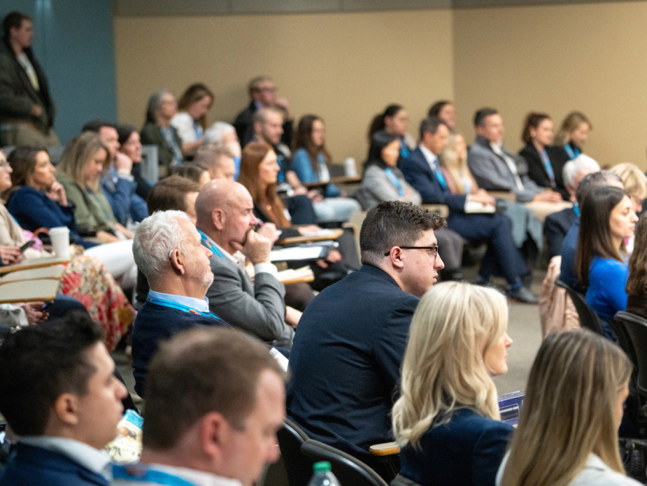 Audience members listening to session speaker in auditorium at 2024 German American Business Summit.