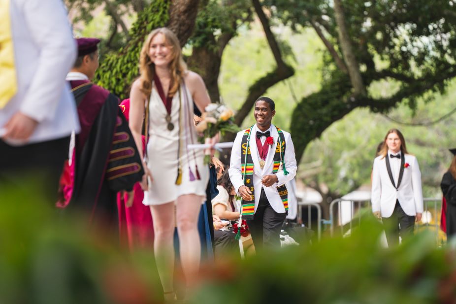 Honors College graduates Madeline Davis and James Dockery walk across the Cistern Yard stage during the 2024 graduation ceremony.