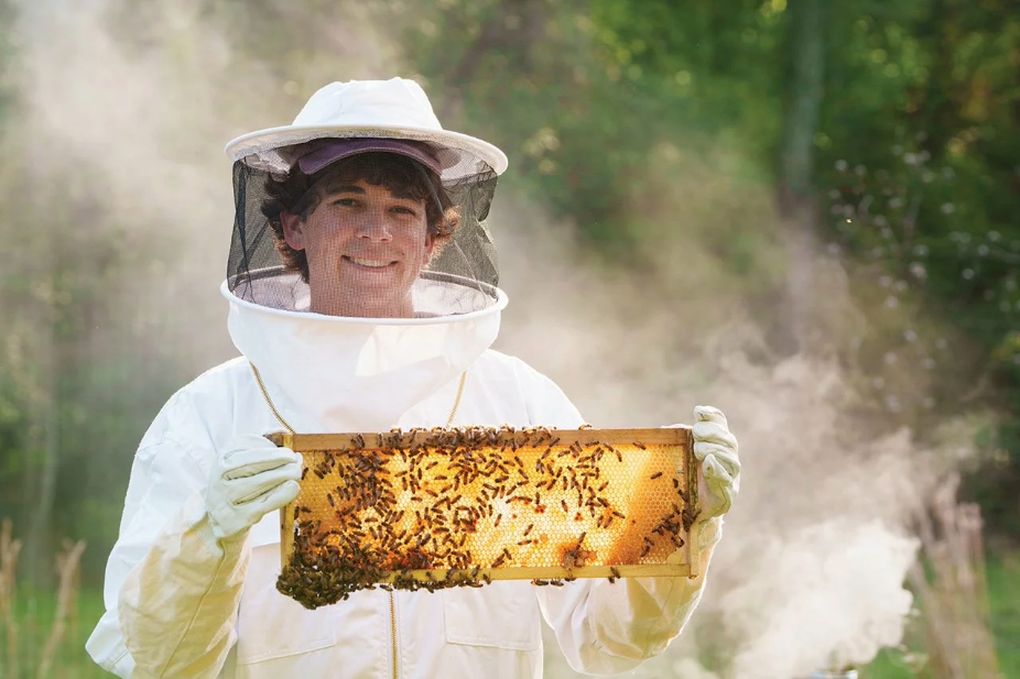 Honors student William Helfgott dons a beekeeper outfit to procure honey