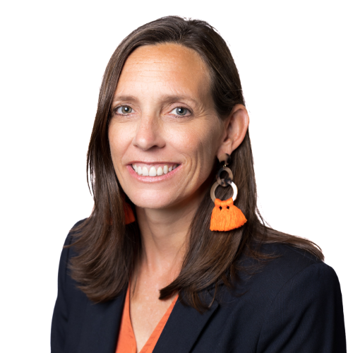 Professional headshot of a woman with shoulder-length brown hair, wearing orange tassel earrings and a dark blazer.