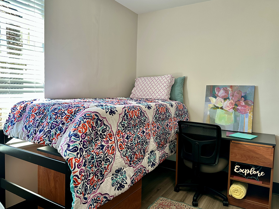 semi-lofted bed with desk and chair at the head of bed