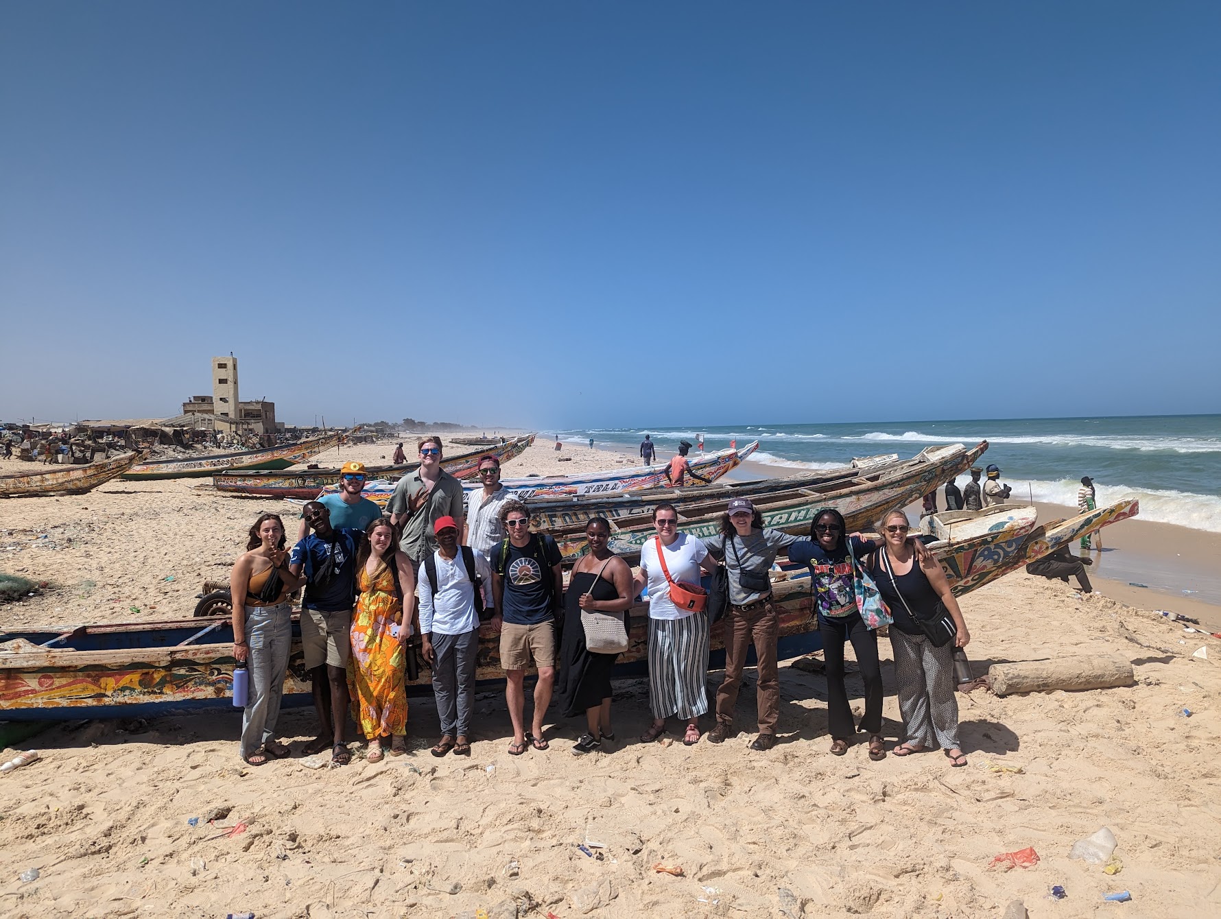 Students standing in front of a boat on the beach, St. Louis, Senegal