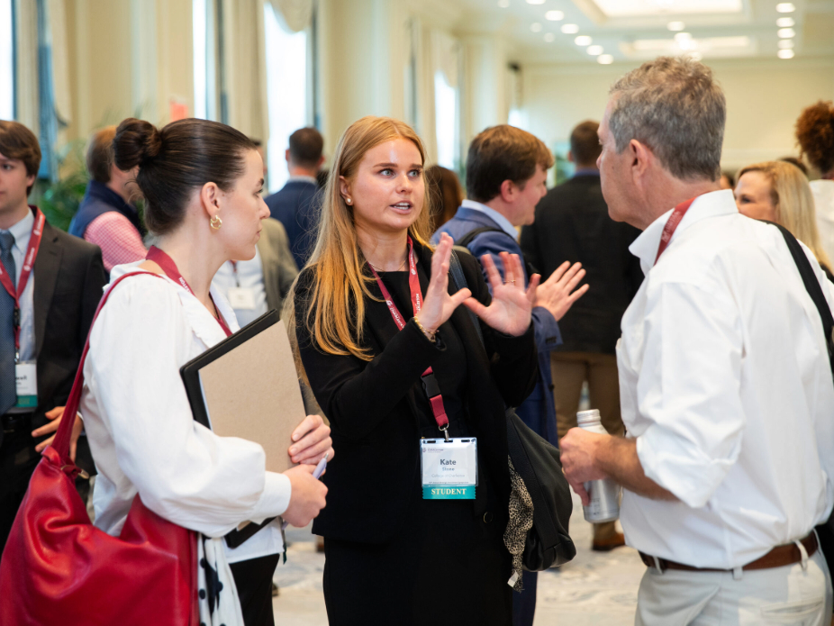 Two women speaking with a man at a conference setting