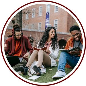 three students sitting outside working together with laptops and books