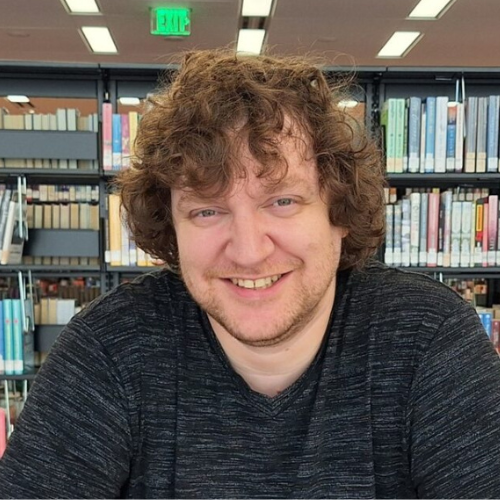 Aaron Barrett seated in front of book shelves