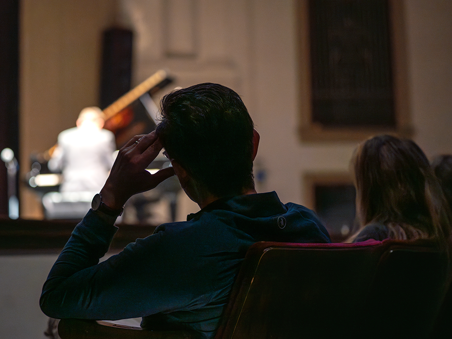 A person watching a piano performance at College of Charleston.
