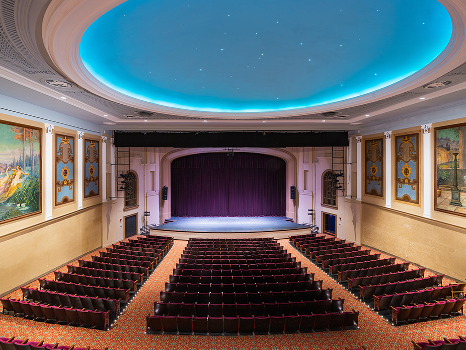 A theatre with a blue starlight ceiling and empty seats.