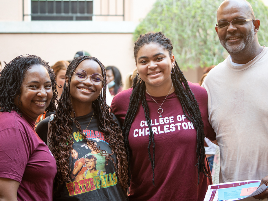 Family of four smiling individuals, including students and adults, dressed in casual attire, with one wearing a College of Charleston shirt.