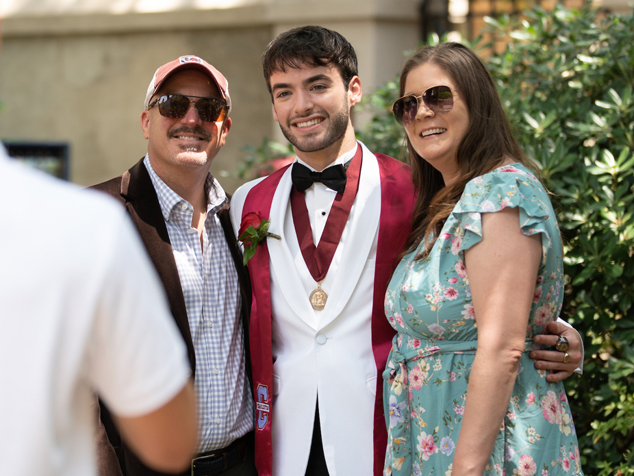 A smiling CofC student wearing a blue Bosch polo stands confidently in front of the Bosch company logo and neatly trimmed shrubbery.