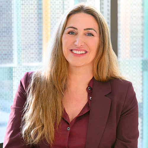 portrait of woman in a burgundy suit sitting at a table