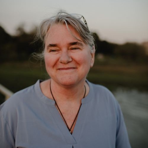 Professional portrait of Jen Cole Wright, a smiling woman with short hair in an outdoor setting.