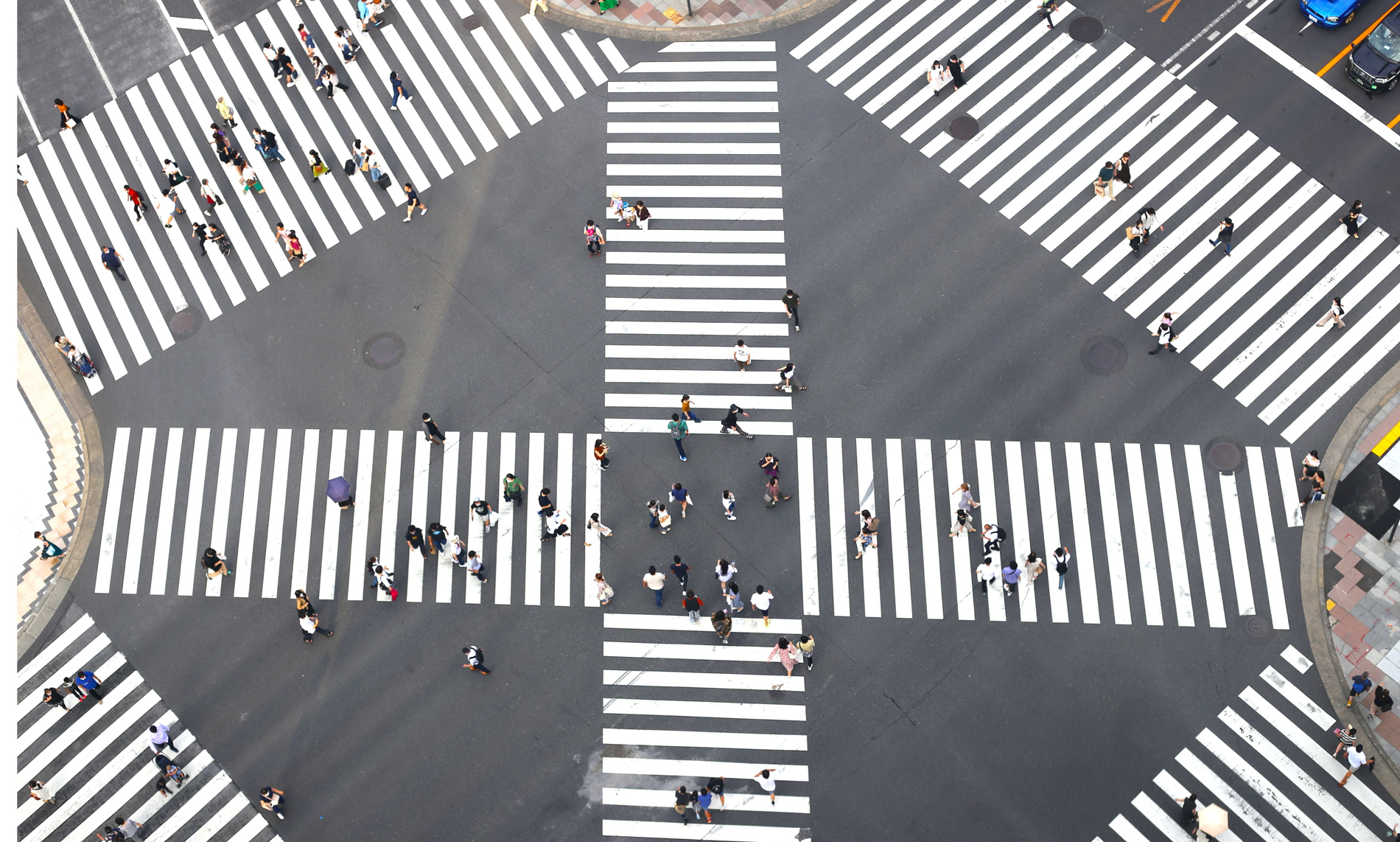 Aerial view of a pedestrian scramble with crosswalks in multiple directions and pedestrians crossing.