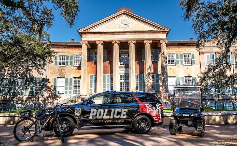 Campus police SUV and small utility cart parked in front of a historic college building with tall columns and green shutters.