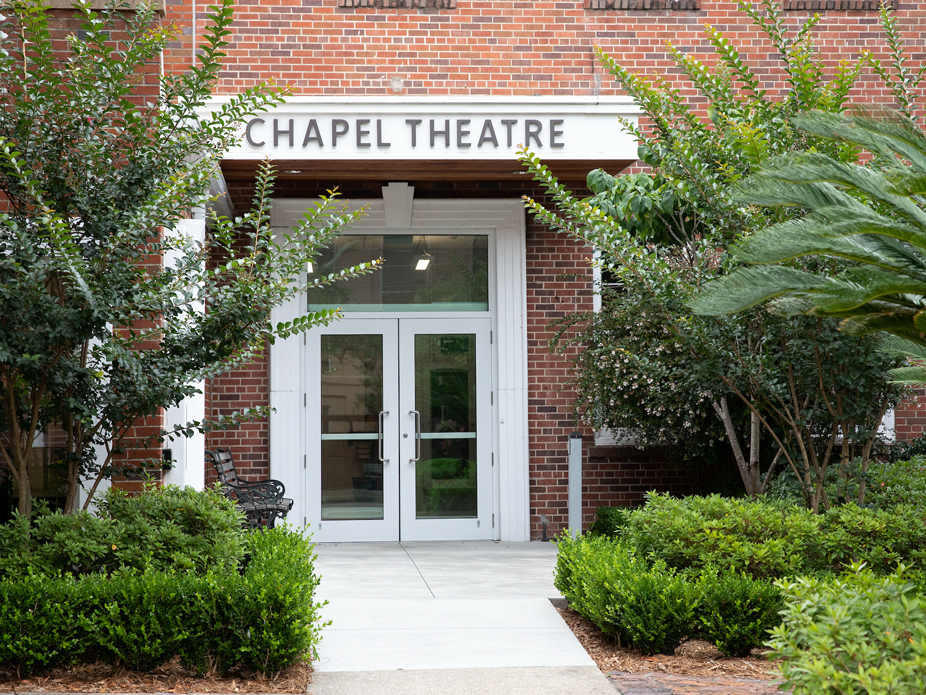 Entrance of the Chapel Theatre, featuring a modern design and surrounded by greenery.