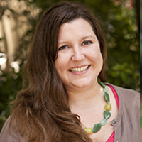 Portrait of Emma Allen, a smiling woman with long brown hair wearing a colorful beaded necklace.