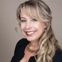 Professional headshot of Jamie Host, a woman with long, wavy blonde hair and a warm smile, wearing a black blouse and a gold necklace.