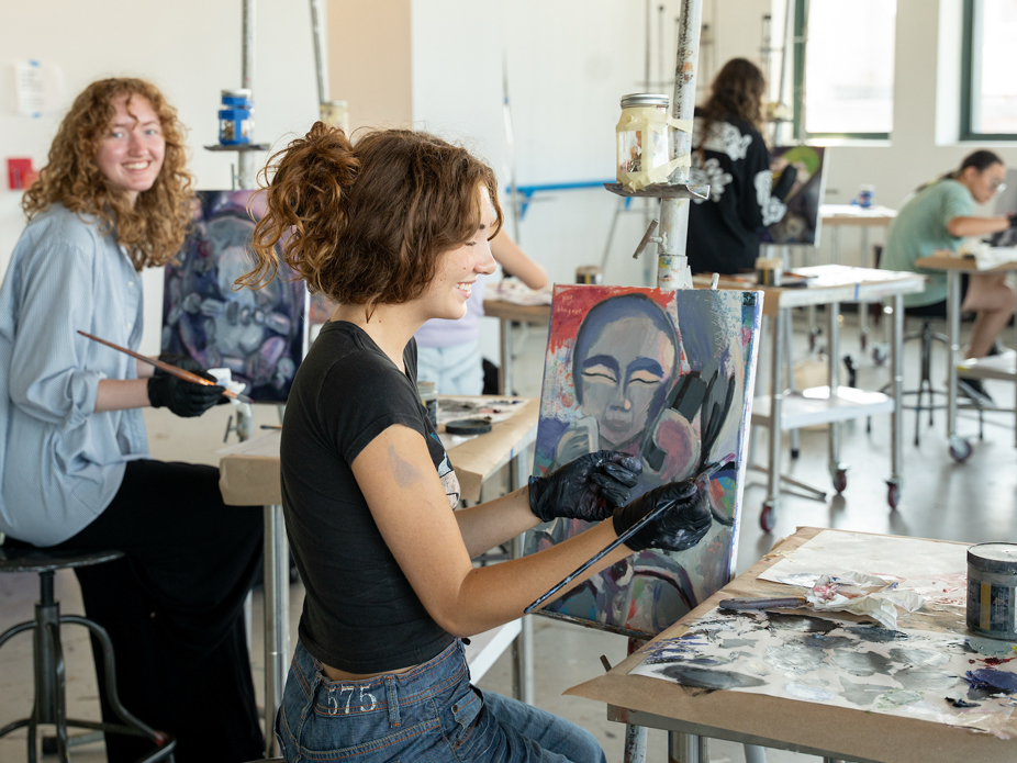 Students in a Studio Arts painting class work on their paintings in reds, blues and grays. 