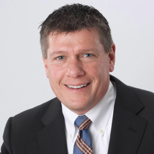 Professional headshot of a smiling man in a business suit with a tie.
