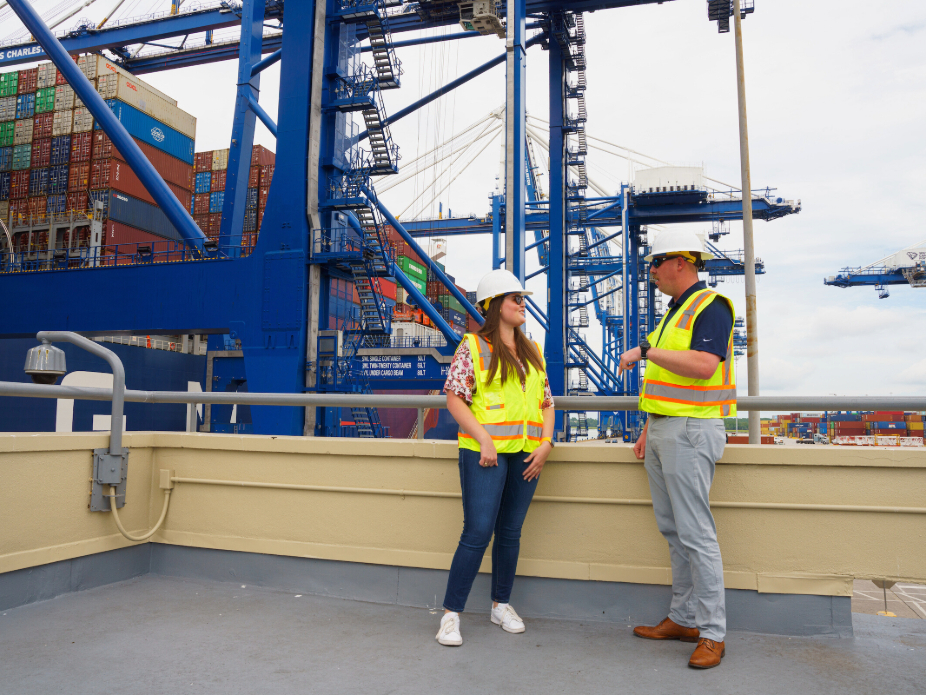 A woman and man at a Port location with hardhats