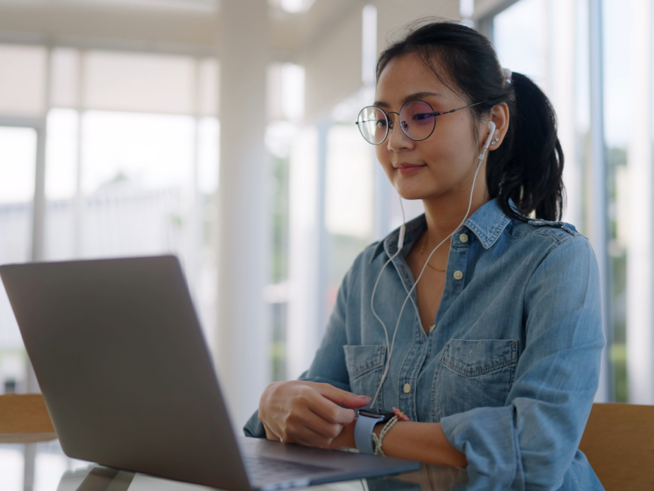 A woman with headphones in on her laptop