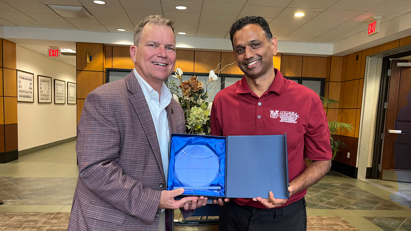 Two people posing with an award between them