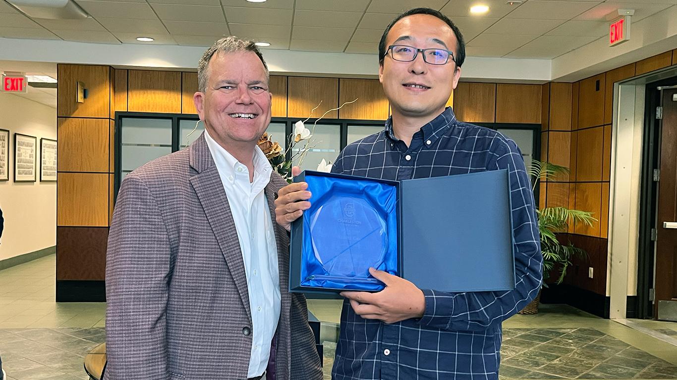 Two people posing with an award between them