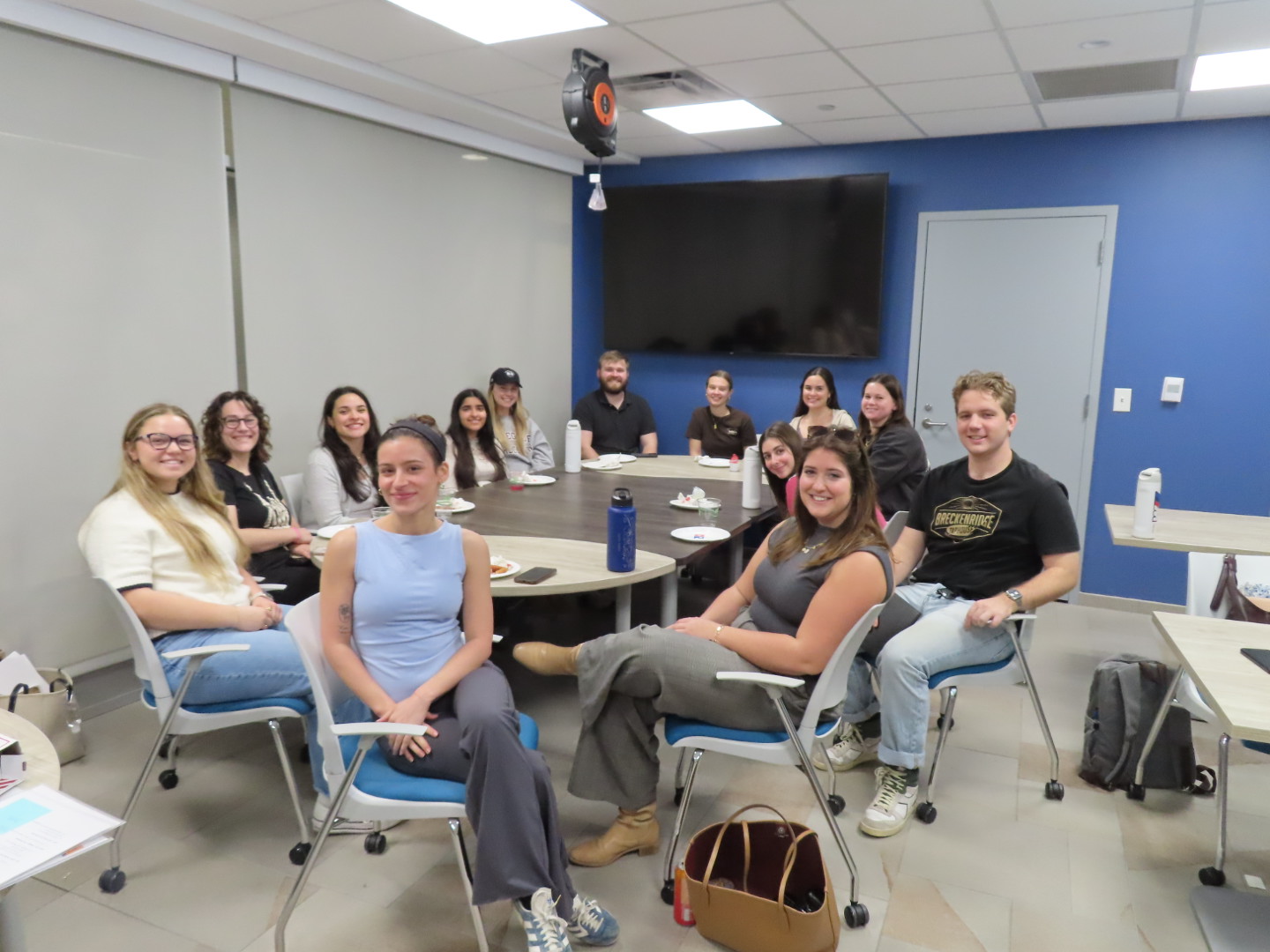 A group of people smiling at a table in a room.