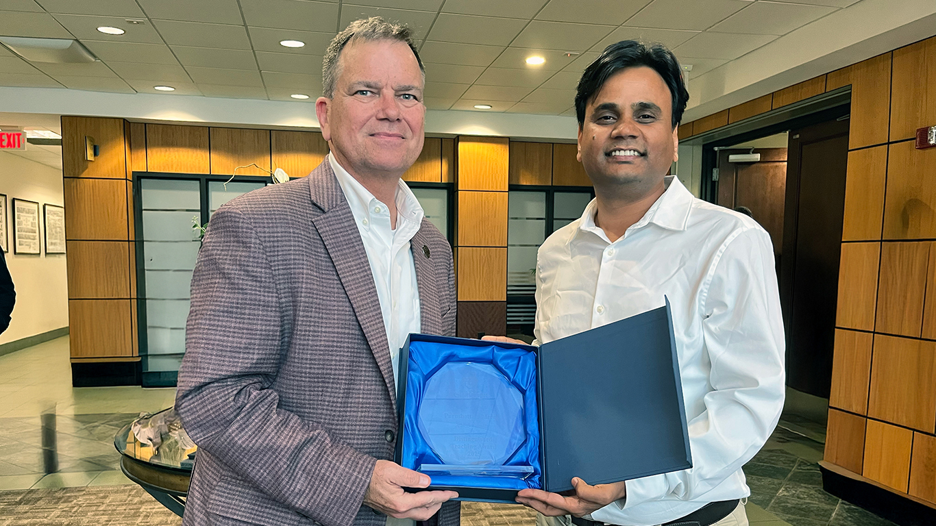 Two people posing with an award between them