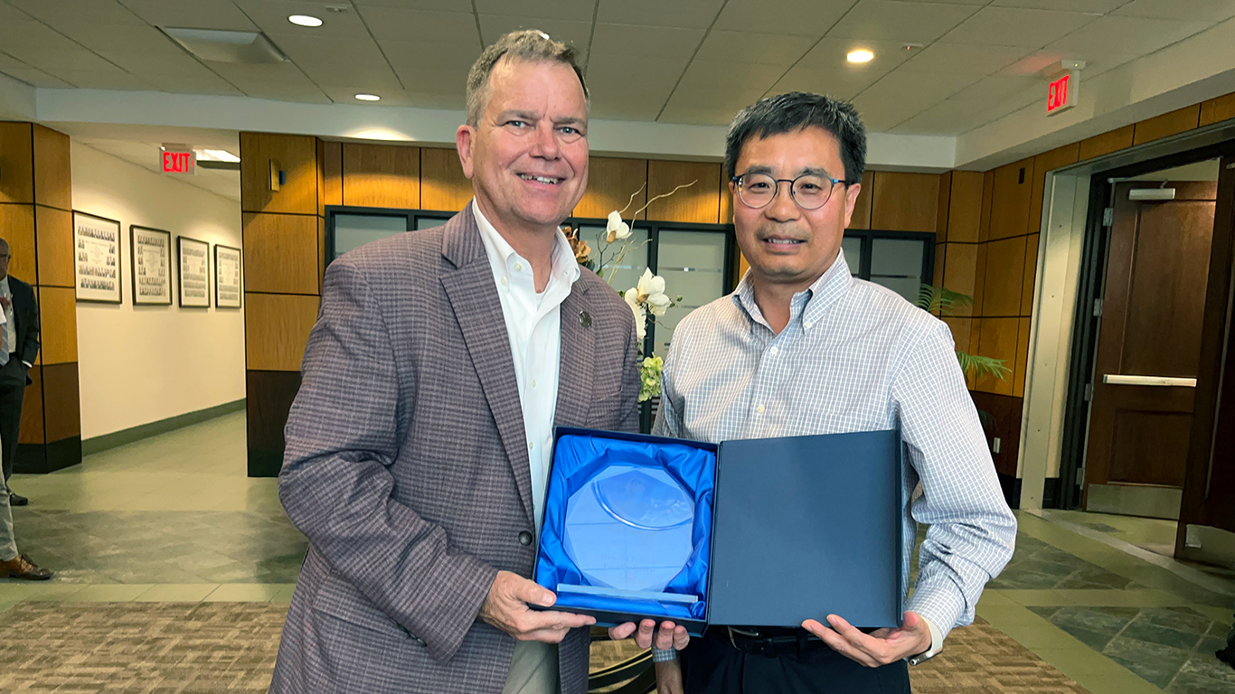 Two people posing with an award between them