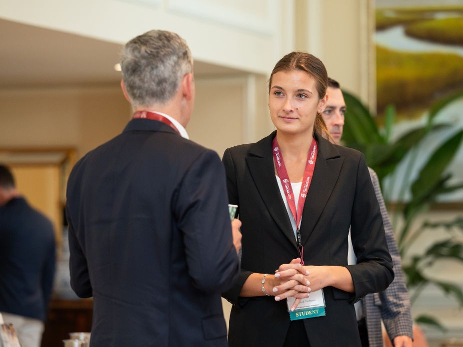 A student at a conference speaking with a professional attendee