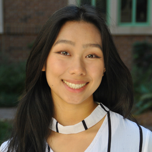 Portrait of Circi Tchang smiling with long dark hair wearing a black and white top.